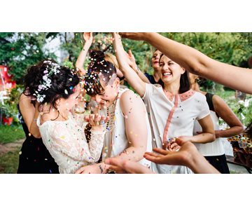 Bröllopspar ler när gäster kastar konfetti över dem