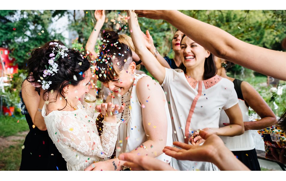 Bröllopspar ler när gäster kastar konfetti över dem