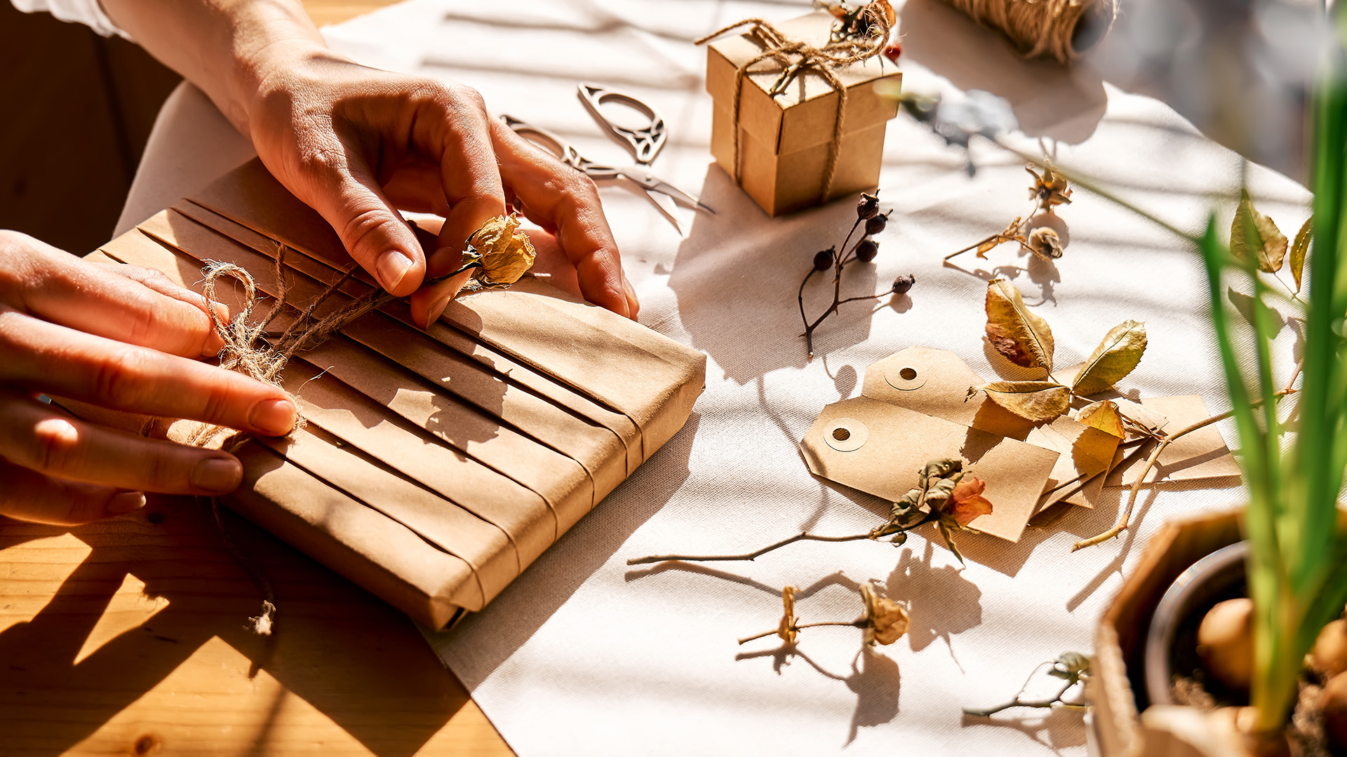Kvinna dekorerar inslagna presenter med återvunnet papper med torkade blommor