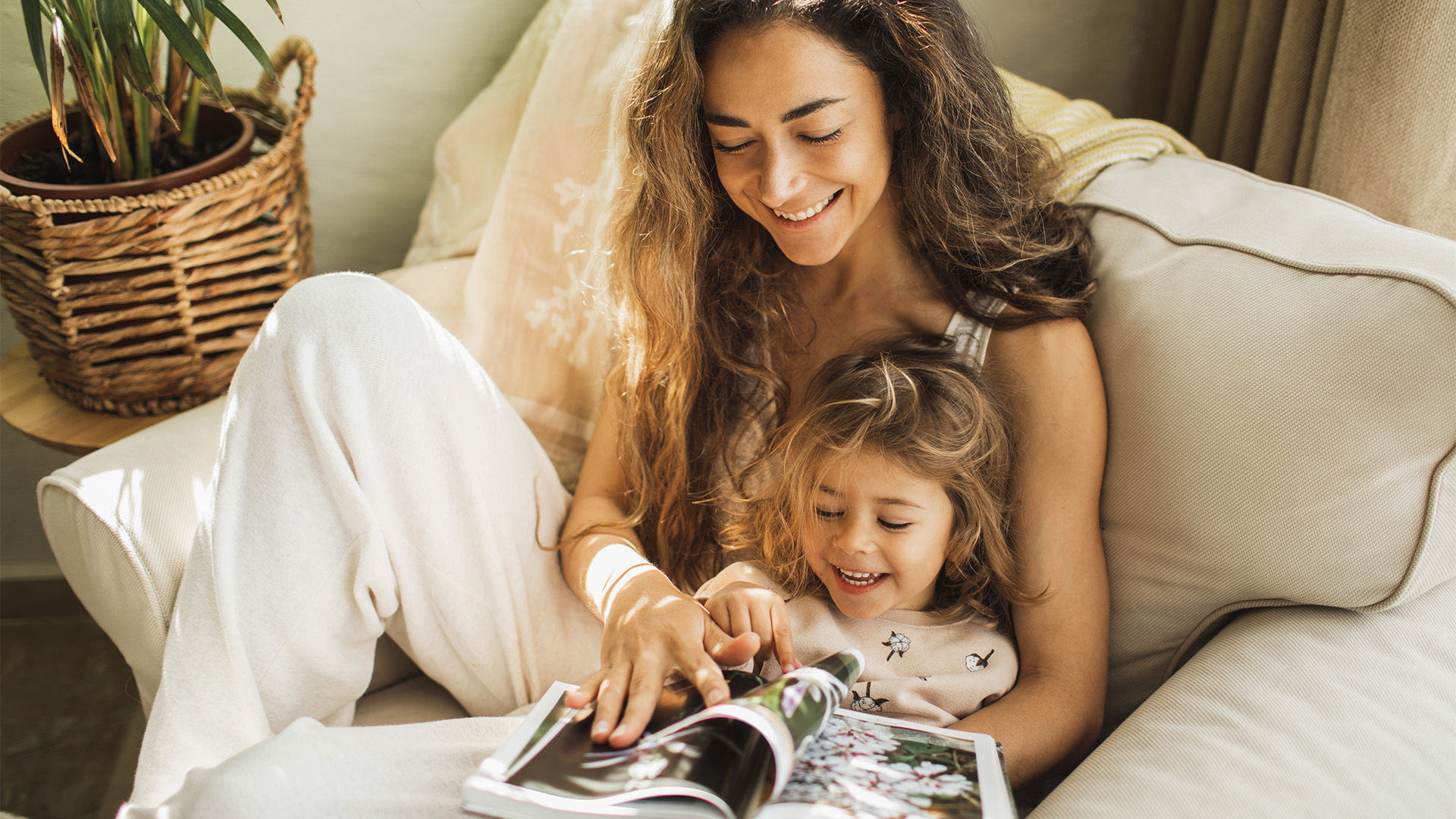 Dam och ett barn som sitter i en fåtölj och tittar på en fotobok