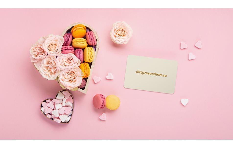Dittpresentkort med hjärtformad ask med makroner och rosor och hjärtformade godis på rosa bakgrund