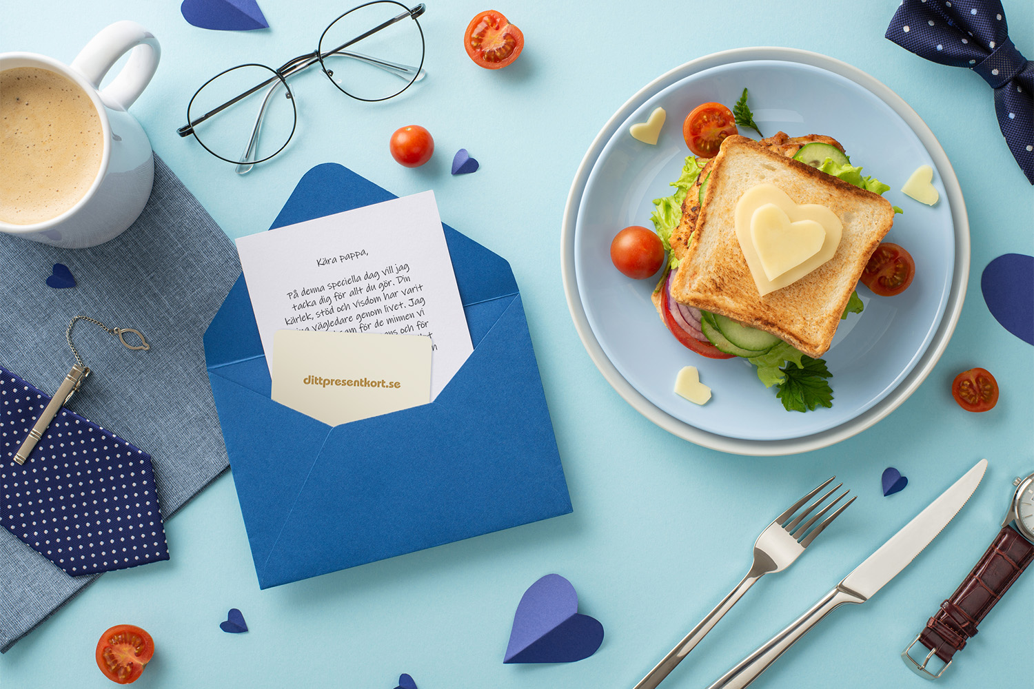Blått kuvert med brev och ditt presentkort, samt en smörgås med tomater och ost format som ett hjärta, och glas, slips, kaffekopp och rosett på blå botten.