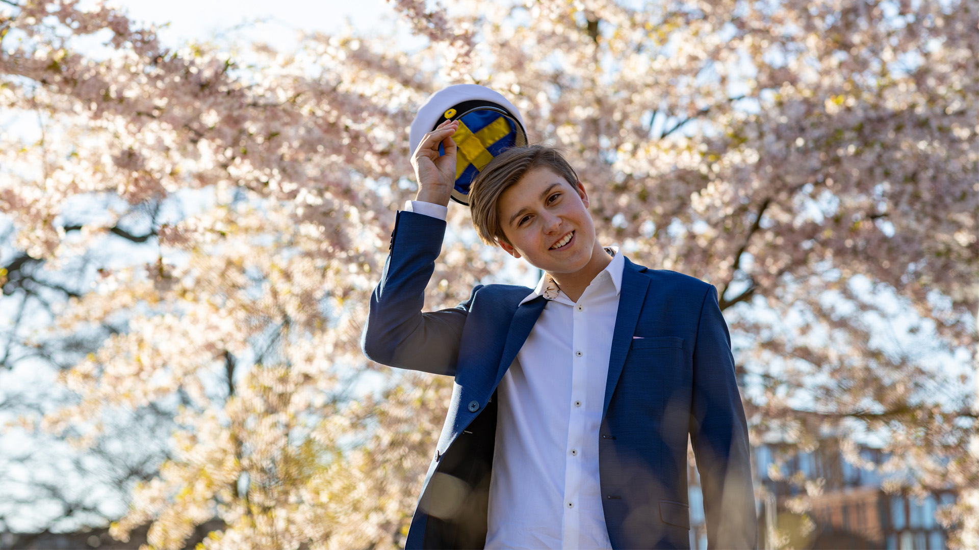 ung pojke poserar i kostym med vit hatt med svenska flaggan