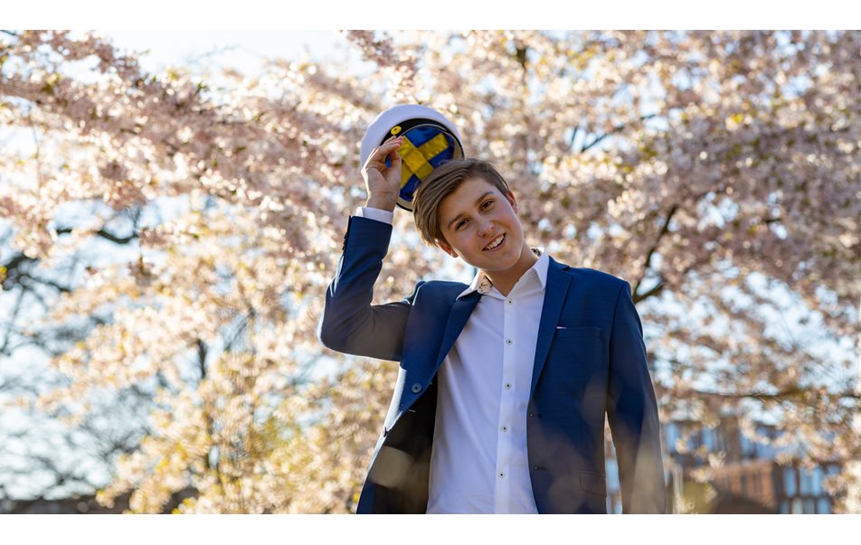 ung pojke poserar i kostym med vit hatt med svenska flaggan